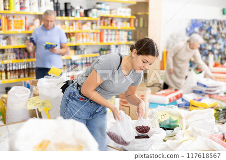 Young woman filling polybag with dried beans in grocery store Young woman filling polybag with dried beans in grocery store 117618567