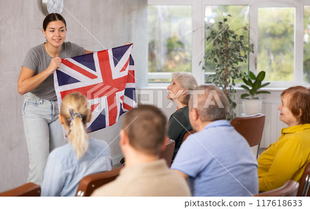 Young female tutor showing flag of United Kingdom in language club 117618633
