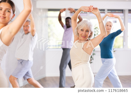 Active men and women of different ages practicing Jazz-funk dance in training hall 117618665