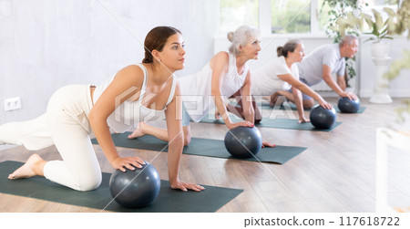 Mature and young lady is on all fours and put one palm on soft ball. Close-up 117618722