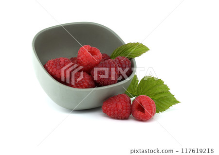 Fresh raspberries in a grey bowl with leaves on white background 117619218