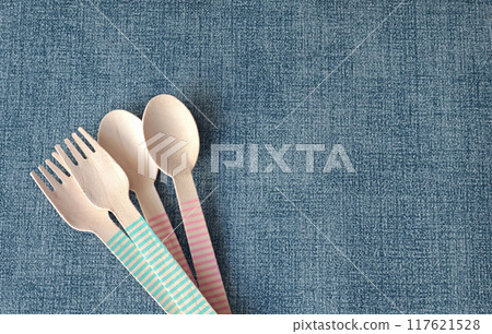 Wooden colorful spoons and forks on mat under plate. Disposable eco-friendly tableware. Food and snacking. Background for design. Wooden colorful spoons and forks on mat under plate. Disposable eco-friendly tableware. Food and snacking. Background for design. 117621528