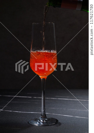 Pour well-chilled rosé champagne (sparkling wine) into a flute glass 117621780