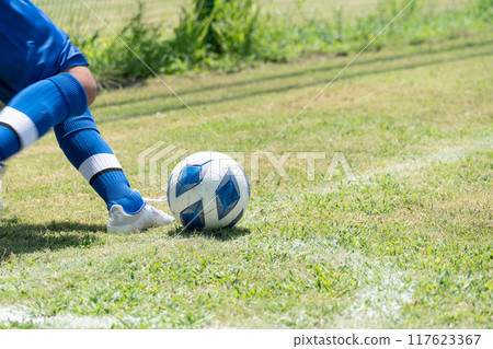An elementary school boy taking a corner kick in a soccer game 117623367