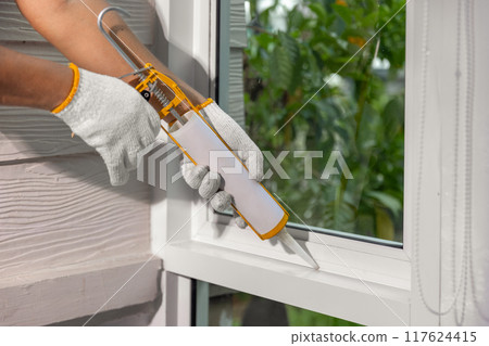 Construction worker using silicone sealant caulk for repair leaked inside window frame. Construction worker using silicone sealant caulk for repair leaked inside window frame. 117624415