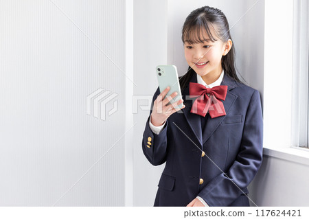 A female junior high school student looking at her smartphone A female junior high school student looking at her smartphone 117624421