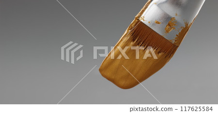 Brush with gold paint on a gray background Brush with gold paint on a gray background 117625584