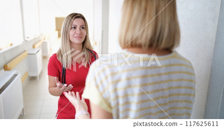 A doctor in listens to a woman in the hospital corridor 117625611