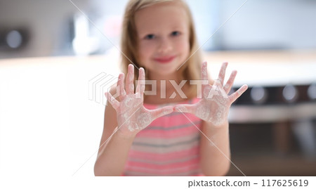 Little joyful girl shows palms in flour, close-up, blurry Little joyful girl shows palms in flour, close-up, blurry 117625619