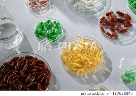Many petri dishes containing different drugs on a white background. Fish oil pills, multivitamins, antibiotics and painkillers... experimental concepts for advertising medicinal products 117626843