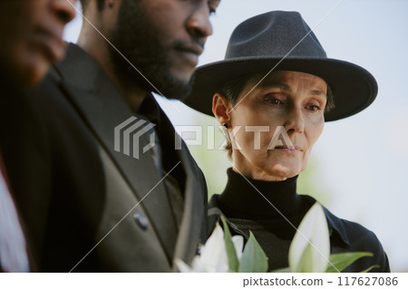 Senior widow visiting with her kids husbands grave and bringing white bouquet to it Senior widow visiting with her kids husbands grave and bringing white bouquet to it 117627086