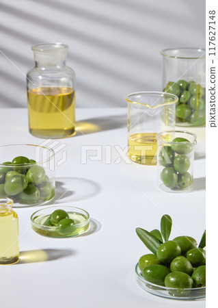 A laboratory setting with fresh olives and essential oils, with a middle space for product placement. Minimal space for cosmetic advertisement. 117627148
