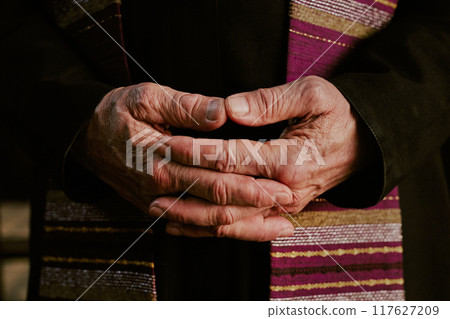 Medium close up of wrinkled unrecognizable male hands of priest 117627209