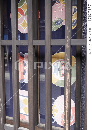 Tsumago-juku: Old streetscape of traditional houses. Japanese-style design fabric visible behind lattice doors. 117627387