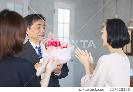 A father receiving a bouquet of flowers from his family on his retirement A father receiving a bouquet of flowers from his family on his retirement 117628300