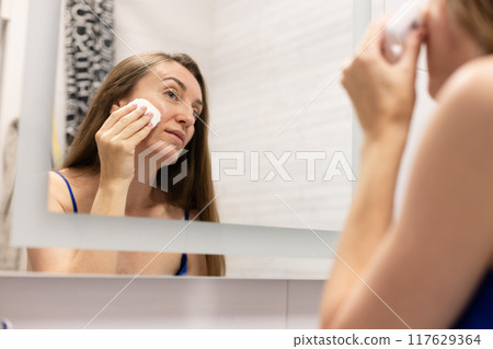 Smiling woman using cream stick to smooth out wrinkles on her face or like sun protection cream stick. 117629364