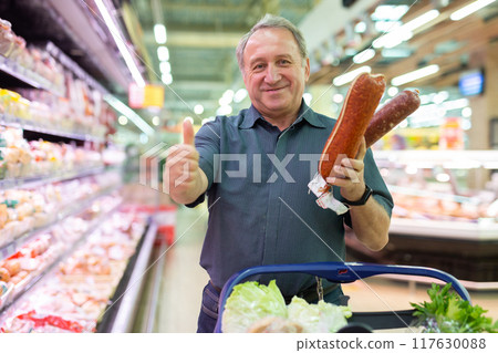 Elderly male customer looking for sausage in meat section of supermarket Elderly male customer looking for sausage in meat section of supermarket 117630088