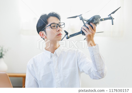 A man inspecting and maintaining a drone at home 117630157