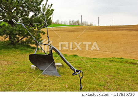 Agricultural manual plow on the grass. Metal plow for plowing fields Agricultural manual plow on the grass. Metal plow for plowing fields 117630720