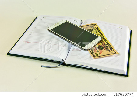 Diary with him lying on a smartphone and a denomination of $ 50 on a white background 117630774