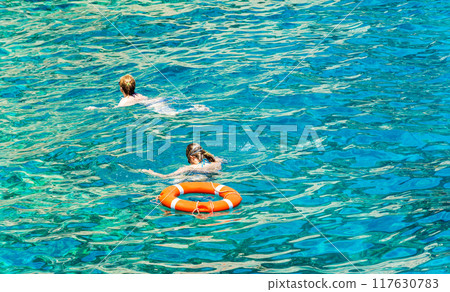 Two women floating in the sea near the lifeline. In beryuzovoy water near the lifeline two women float Two women floating in the sea near the lifeline. In beryuzovoy water near the lifeline two women float 117630783