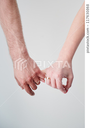 Close up of man's and woman's hands taking each other for little fingers. Married couple holding hands. Concept of love, intimacy, support, and trust. Close up of man's and woman's hands taking each other for little fingers. Married couple holding hands. Concept of love, intimacy, support, and trust. 117630868