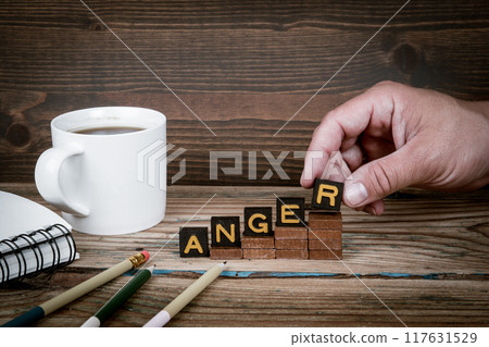 ANGER. Old letter tiles on wooden steps, development concept 117631529