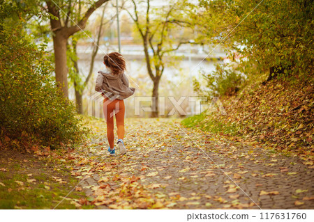 Seen from behind woman in fitness clothes in park jogging Seen from behind woman in fitness clothes in park jogging 117631760