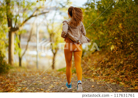 Seen from behind trendy woman in fitness clothes in park jogging 117631761