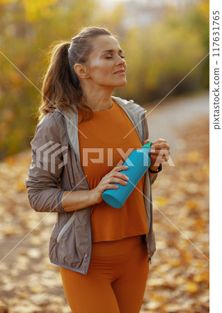 relaxed modern female in fitness clothes in park 117631765