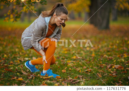 sad modern woman in fitness clothes in park 117631776