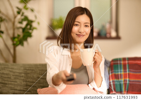 Middle-aged woman drinking coffee while relaxing on the sofa Middle-aged woman drinking coffee while relaxing on the sofa 117631993