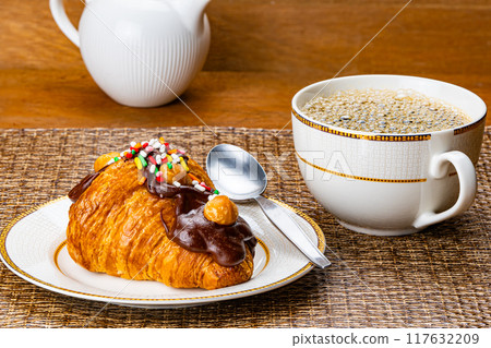 Croissant garnished with chocolate and rainbow sprinkles. 117632209