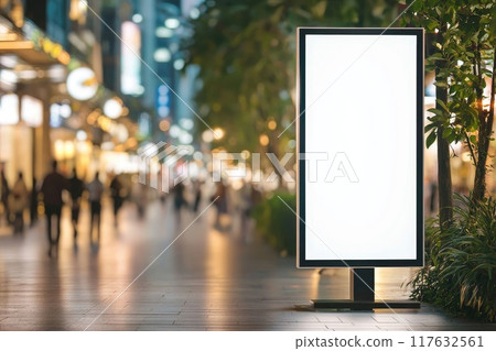 An empty white vertical billboard on the street in the city center with people walking around and green trees and plants An empty white vertical billboard on the street in the city center with people walking around and green trees and plants 117632561