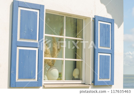 White House with blue shutters and vases on the windowsill on the beach . High quality photo 117635463