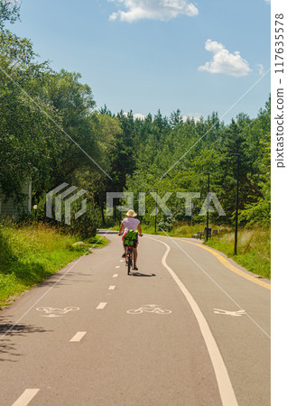 Woman riding a bike on country road in sunny summer day. High quality photo 117635578