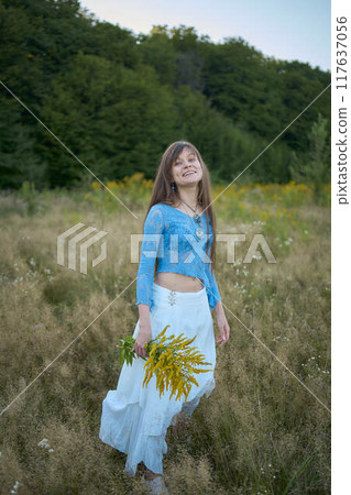 woman in whimsical aesthetic style dress in field in summer at sunset 117637056