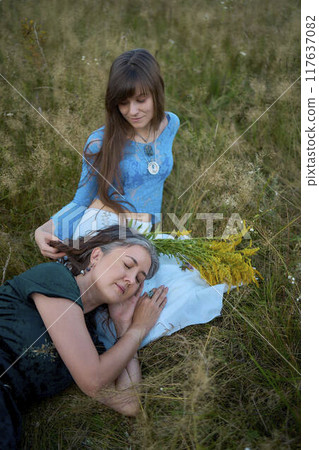 two woman in a whimsical aesthetic style dress in a field in the summer at sunset two woman in a whimsical aesthetic style dress in a field in the summer at sunset 117637082