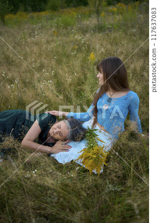 two woman in a whimsical aesthetic style dress in a field in the summer at sunset two woman in a whimsical aesthetic style dress in a field in the summer at sunset 117637083