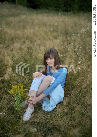 woman in whimsical aesthetic style dress in field in summer at sunset 117637089