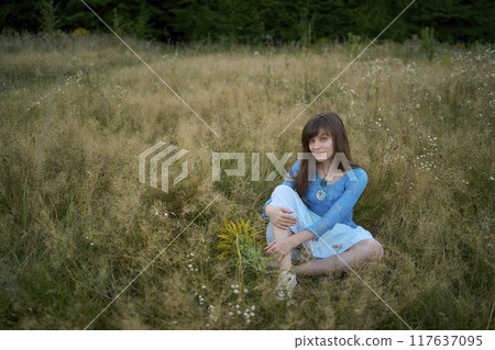 woman in whimsical aesthetic style dress in field in summer at sunset 117637095