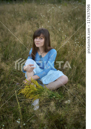 woman in whimsical aesthetic style dress in field in summer at sunset 117637096