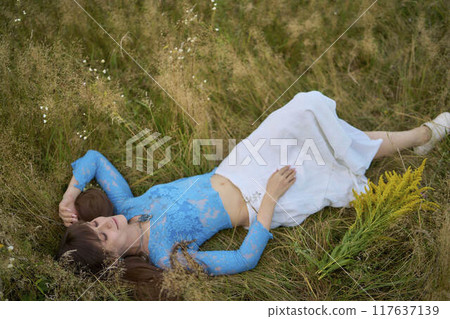 woman in whimsical aesthetic style dress in field in summer at sunset woman in whimsical aesthetic style dress in field in summer at sunset 117637139