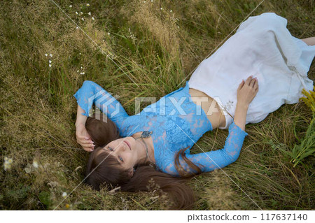 woman in whimsical aesthetic style dress in field in summer at sunset woman in whimsical aesthetic style dress in field in summer at sunset 117637140
