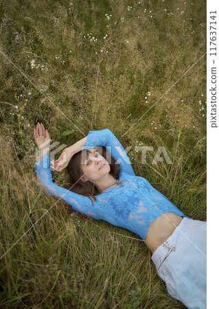 woman in whimsical aesthetic style dress in field in summer at sunset woman in whimsical aesthetic style dress in field in summer at sunset 117637141