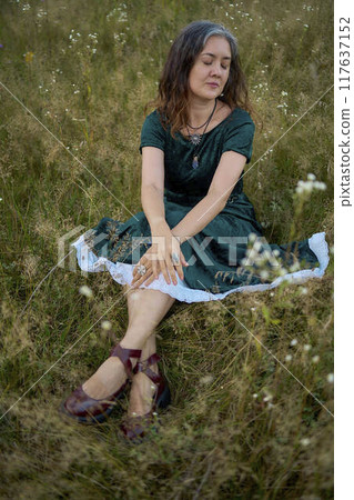 woman in whimsical aesthetic style dress in field in summer at sunset woman in whimsical aesthetic style dress in field in summer at sunset 117637152