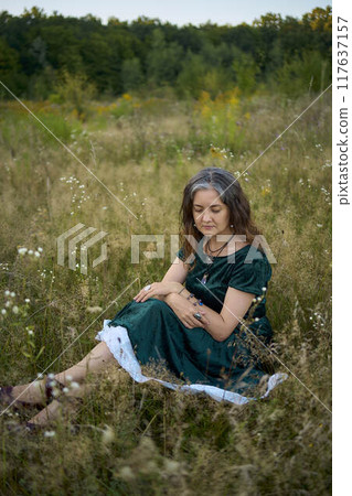 woman in whimsical aesthetic style dress in field in summer at sunset woman in whimsical aesthetic style dress in field in summer at sunset 117637157