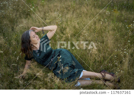 woman in whimsical aesthetic style dress in field in summer at sunset woman in whimsical aesthetic style dress in field in summer at sunset 117637161
