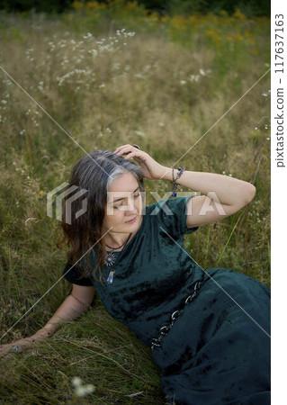 woman in whimsical aesthetic style dress in field in summer at sunset woman in whimsical aesthetic style dress in field in summer at sunset 117637163