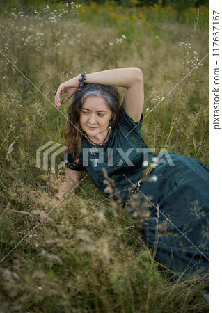 woman in whimsical aesthetic style dress in field in summer at sunset 117637167
